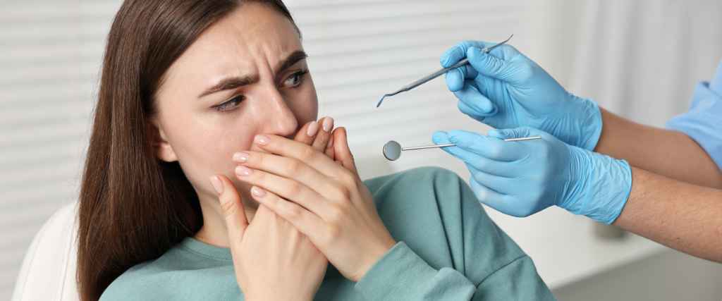 Woman with dental anxiety shying away from dental tools at dentists office
